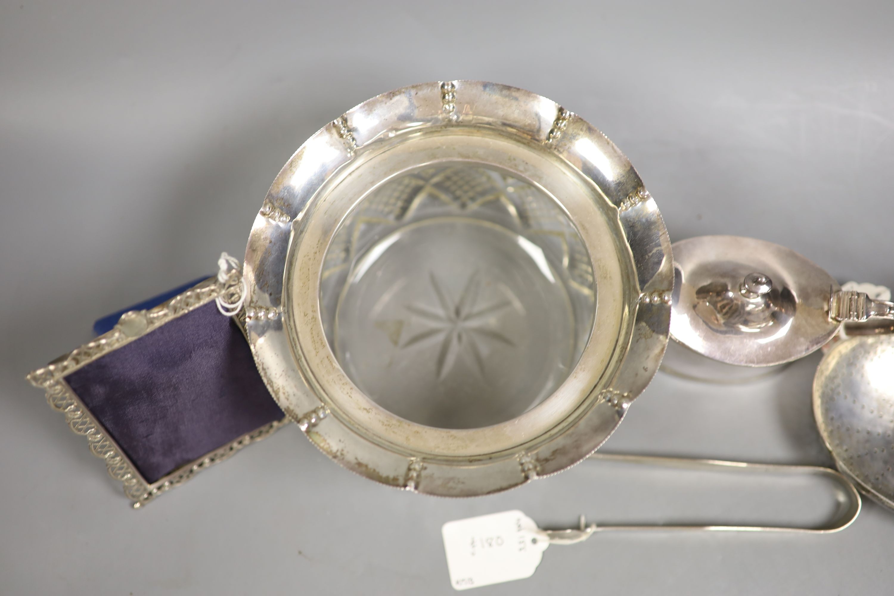 A small selection of decorative silver items to include a Georgian pierced strainer, a mustard pot, pair of sugar tongs and a mounted glass jar (lacking cover).